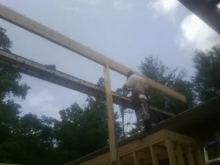 Carpenter setting a ridge beam over a new addition frame — Ice Dam Removal by Roofing Brothers in Whipple