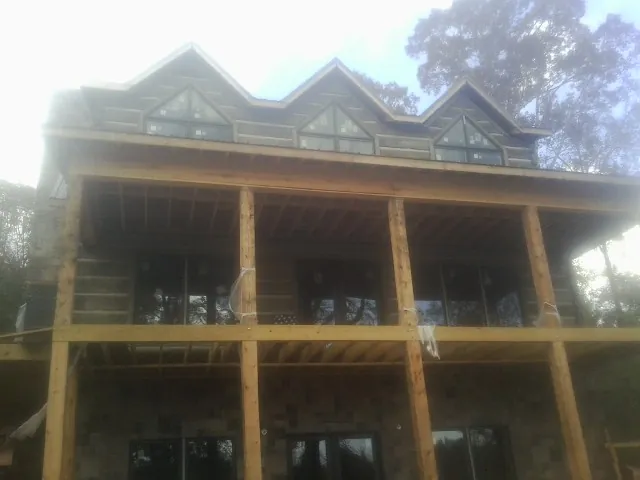 Dormers and porch framing on a large log home under construction — Roof Coating work by our crew in Whipple