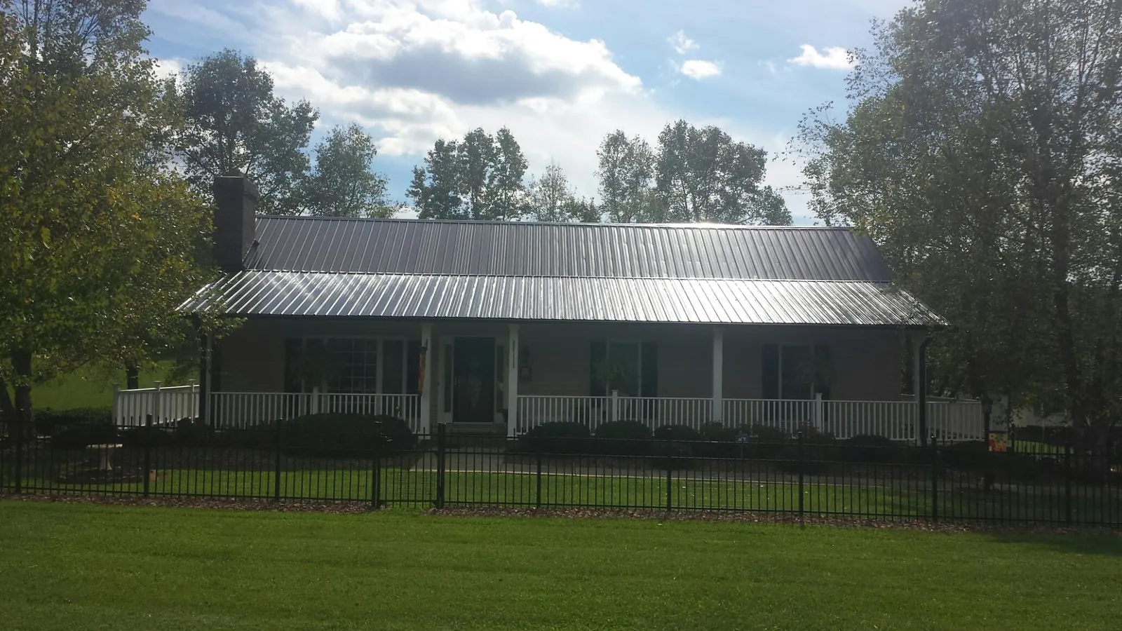 Gray metal roof on a brick ranch with a full width front porch — Gutter Guard Installation work by our crew in Whipple