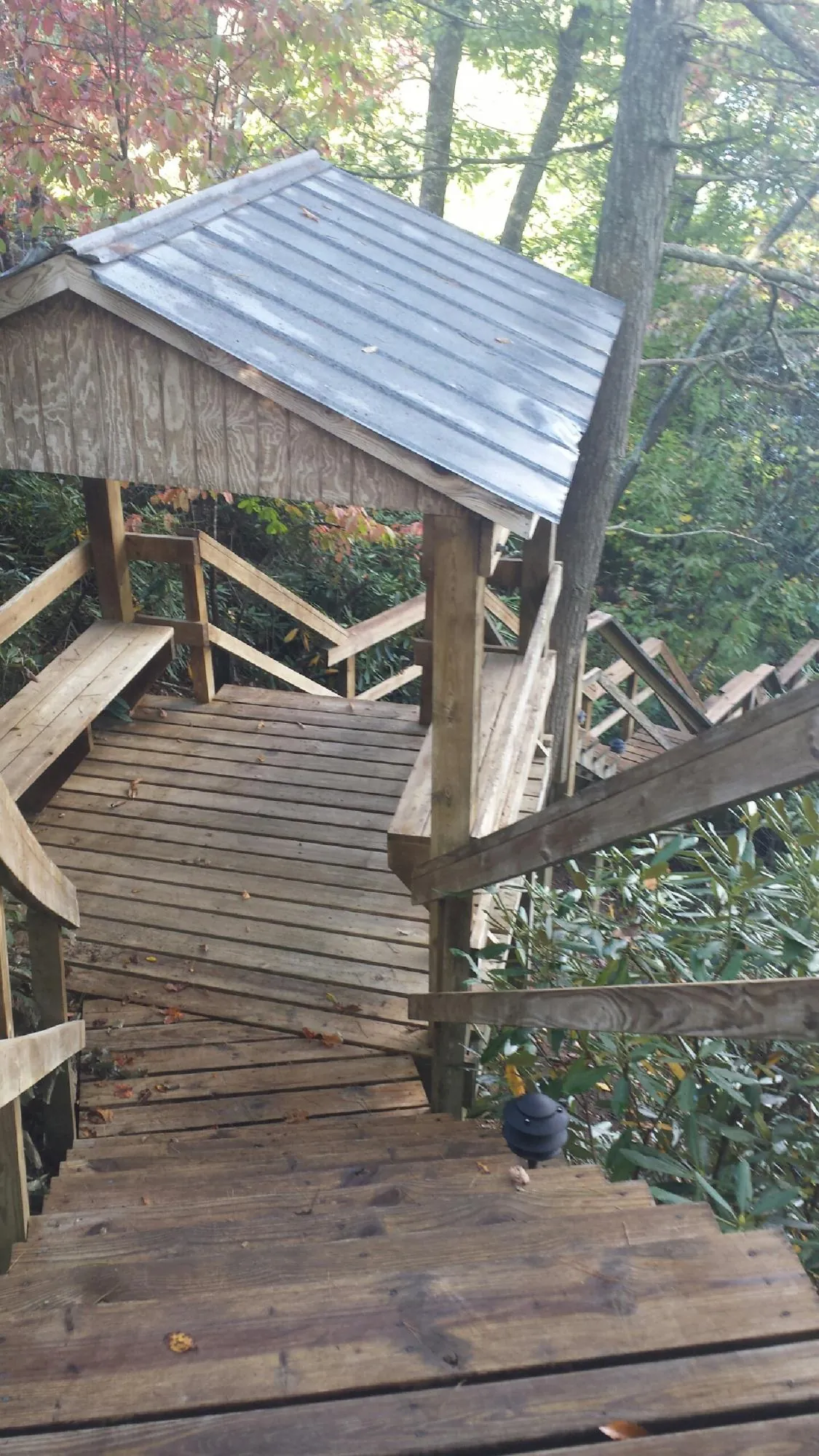Metal roofed shelter over wooden steps on a wooded walkway — Skylight Repair & Installation work by our crew in Whipple