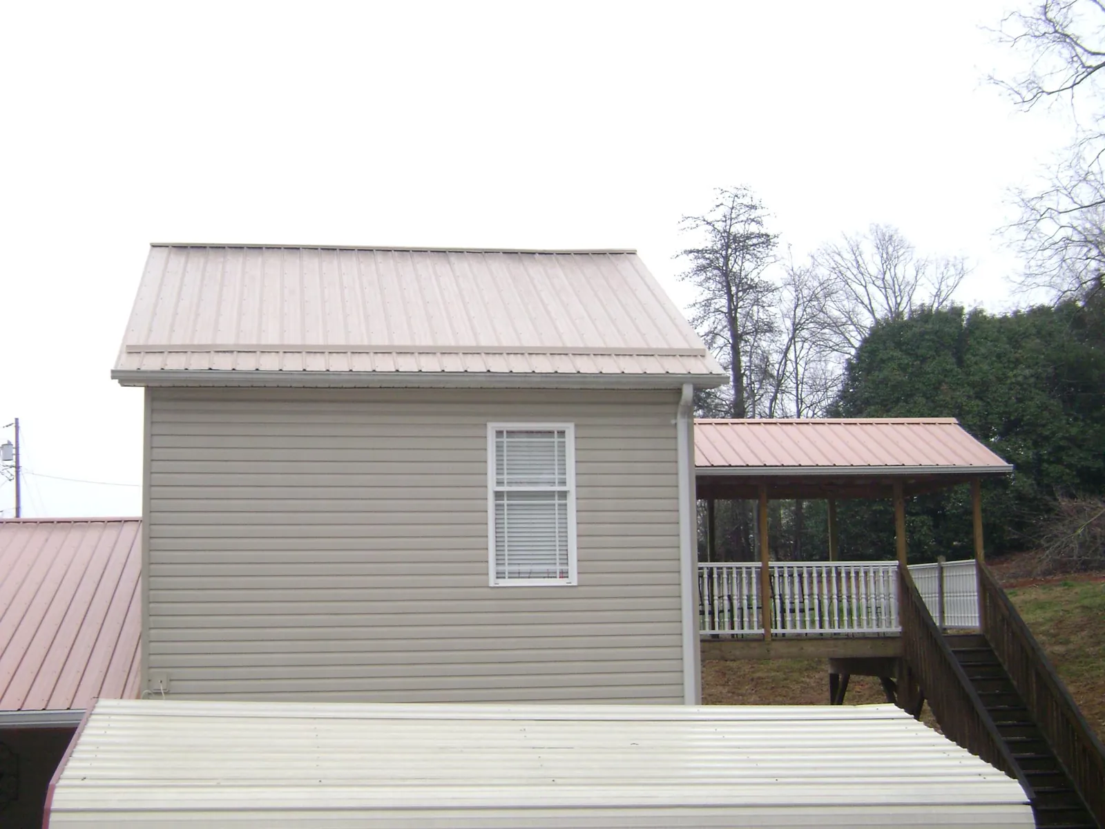 Tan metal roofs on a two story addition and attached porch, from a Roof Replacement job in Whipple